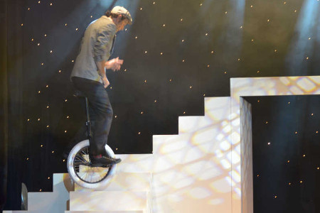 Un monocycliste monte les grands escaliers blancs de la revue du cabaret.