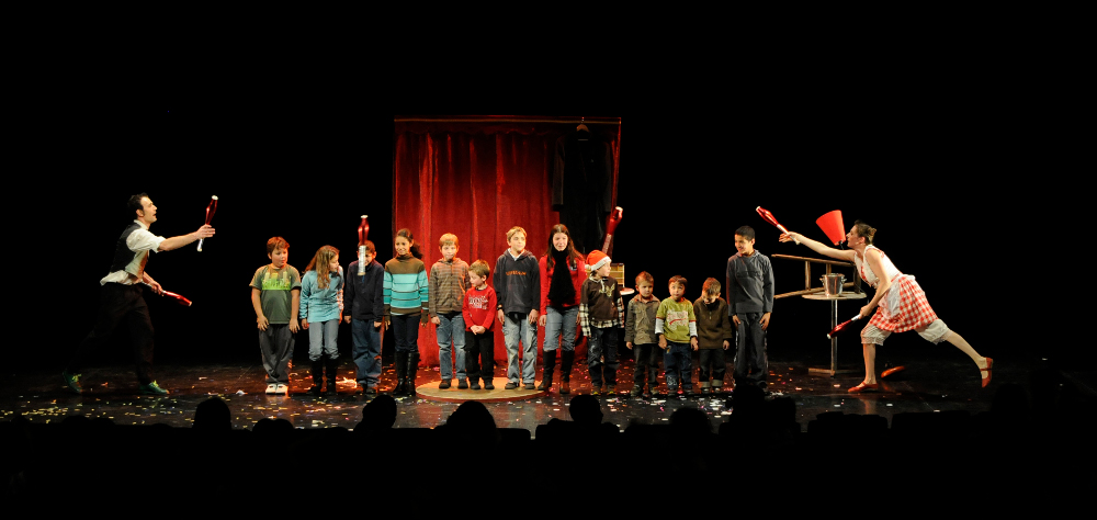 Sur scène les artistes font un passing avec 6 massues rouges autour de 13 enfants alignés face public. Au sol il y a plein de confettis.